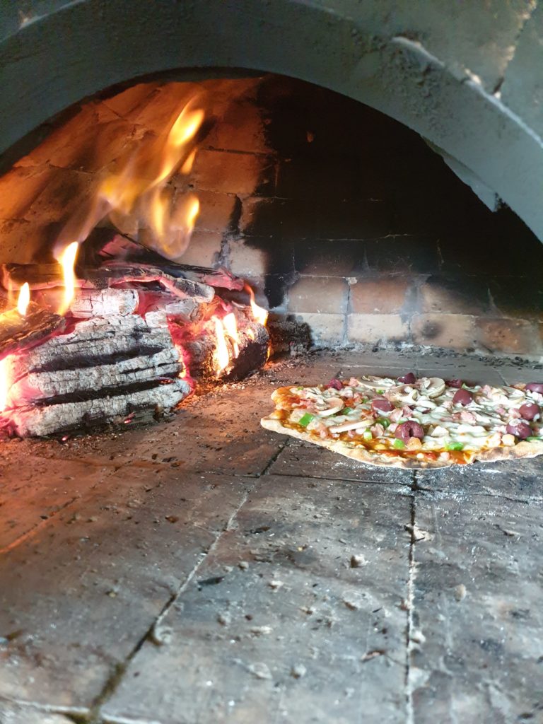 flames touching the oven roof while baking delicious homemade pizza